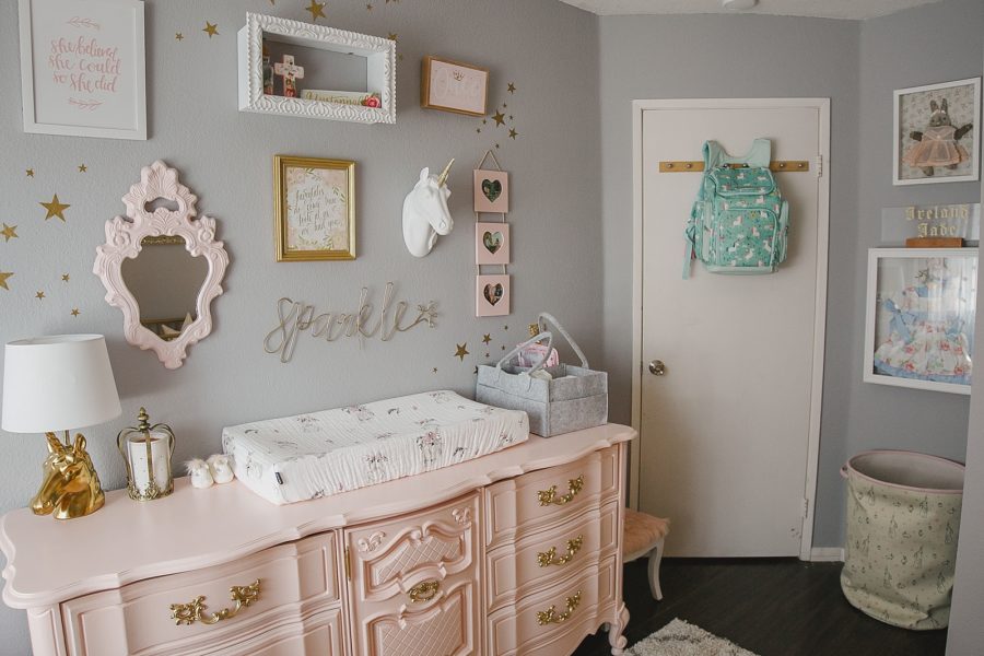 Baby girl nursery with pink and gold dresser and gray walls