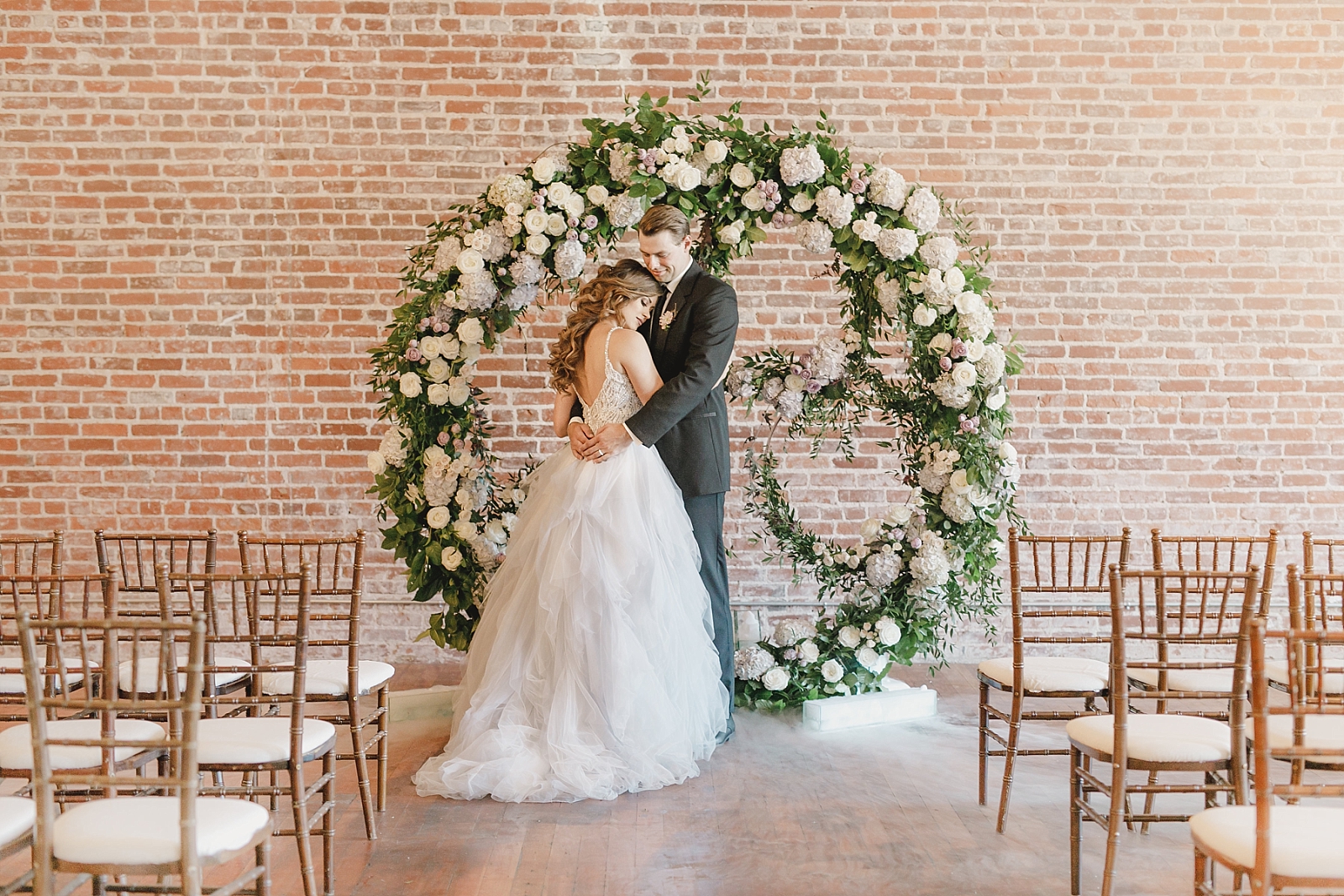 Bride and groom with floral arch ceremony backdrop